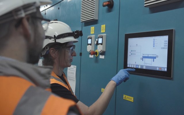 Workers in hard-hats looking at a screen