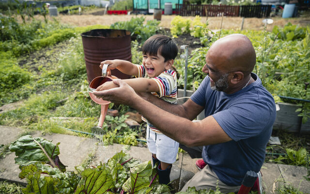 An adult and child using a watering can together