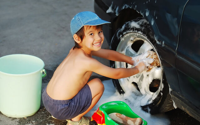 A child washing a car wheel by hand