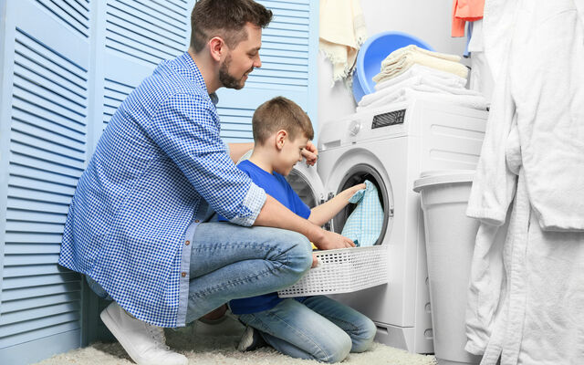 Adult and child loading a washing machine