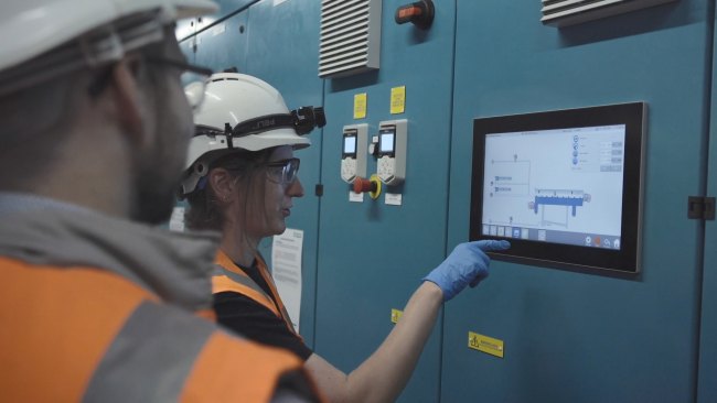 Workers in hard-hats looking at a screen